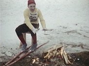 En sittande skidlöpare värmer händerna över en brasa.