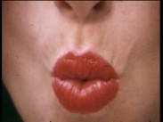 Närbild av en kvinnas rödmålade läppar formade inför en puss.