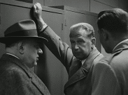 Dag Hammarskjöld lutad mot ett skåp flankerad av två män.
