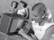 Tre unga kvinnor på badklippor, en rattar på en radio.