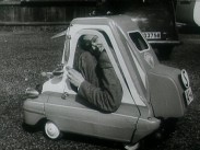 En man sitter dubbelvikt i Sveriges minsta bil.