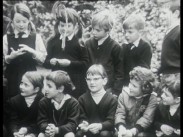 Tio skolbarn i lågstadieåldern utomhus, hälften sitter på huk framför de övriga som står upp.