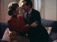En man och en kvinna sitter i en soffa i ett vardagsrum och håller om varandra.