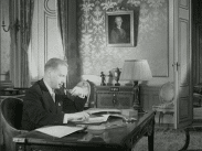 Dag Hammarskjöld vid skrivbordet i sitt arbetsrum, tänder sin pipa.