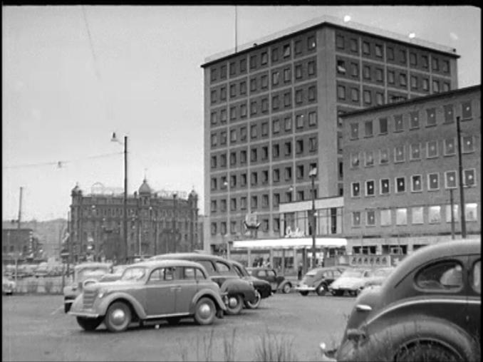 Järntorget i Göteborg med biograf Draken i fonden, parkerade bilar i förgrunden.