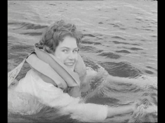 Leende kvinna klädd med flytväst i vatten.